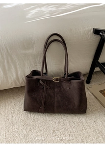 Detail of dark brown matte tote bag with golden horseshoe buckle and dual handles