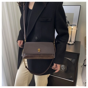 Detail of vintage dark brown leather crossbody bag featuring a golden rotating metal lock