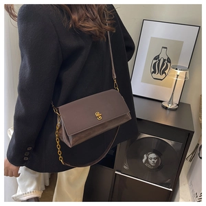 Detail of dark coffee leather crossbody bag with gold metal twist lock and chain strap