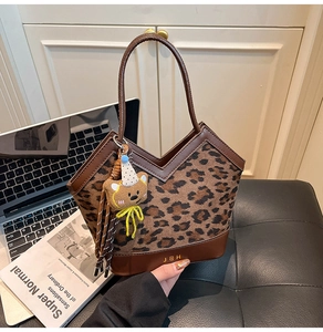 Detail of leopard print handbag with brown leather trim and cute teddy bear charm
