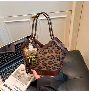 Detail of vintage leopard print tote bag featuring brown leather trim and bear pendant