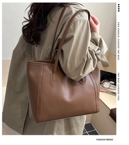 Side view of large brown tote bag on model showing smooth leather texture and stitching