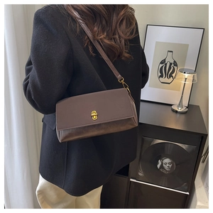 Detailed view of brown leather crossbody bag with golden oval twist lock and mixed textures