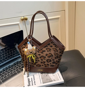 Detail view of leopard print shoulder bag with brown leather trim and cute bear charm