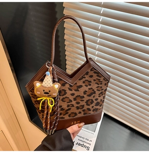 Detail of vintage leopard print tote bag with brown leather trim and bear pendant charm