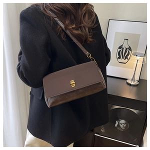 Close-up of vintage brown shoulder bag with golden twist lock and textured chain strap