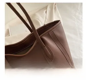 Detailed view of stitching and handle attachment on a vintage brown leather tote bag