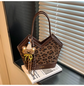 Leopard print tote bag detail with brown leather base and cute bear charm on a book