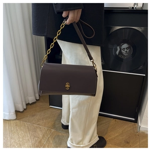 Detail of deep brown rectangular leather handbag with gold twist-lock and chain strap