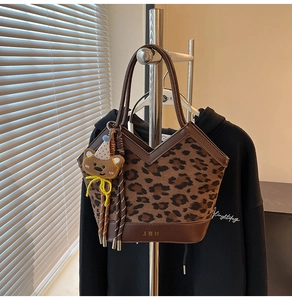 Detailed close-up of leopard print tote bag with gold JDH logo and cute bear pendant