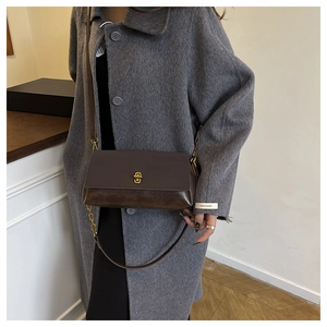 Detailed view of deep brown leather crossbody bag with elegant gold turn-lock closure