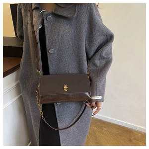 Close-up of vintage dark brown crossbody bag featuring dual leather texture and gold twist lock