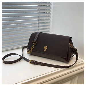 Detail view of brown leather handbag with gold metal lock and adjustable chain strap