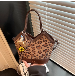Detail of leopard print handbag featuring leather base, gold logo, and cute bear pendant
