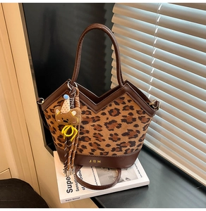 Detail of leopard print tote bag featuring V-cut design and cute teddy bear charm