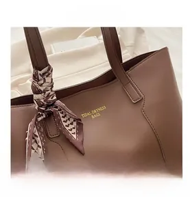 Dettaglio della borsa tote in pelle marrone scuro con elegante foulard di seta