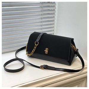 Detail of a black leather crossbody bag with a prominent gold twist lock on white surface