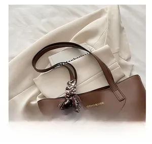 Borsa tote in pelle marrone con logo dorato e foulard in seta su un blazer