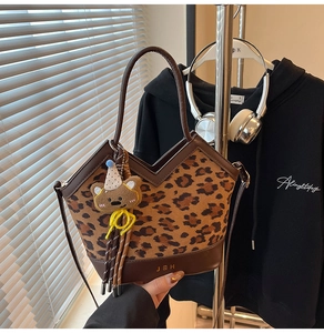 Detail of leopard print tote bag with brown leather base and cute bear charm attachment