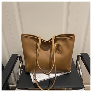 Close-up of a large brown leather tote bag placed on a modern black metal chair