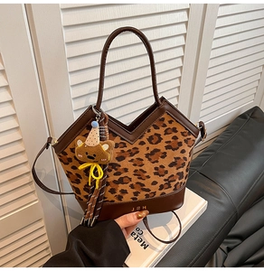 Detail view of leopard print handbag with brown leather trim and cute bear charm pendant