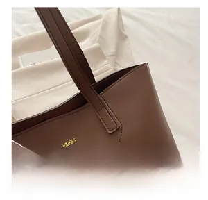Dettaglio della borsa tote marrone con stampa Tidal Dryness dorata e sciarpa di seta
