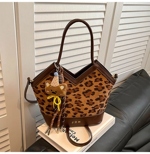 Close-up of leopard print tote bag with metallic JBH letters and plush bear charm