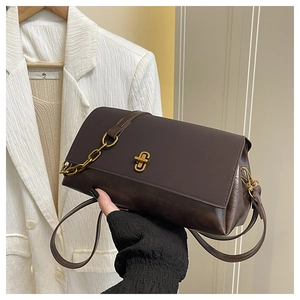 Detailed shot of dark brown crossbody bag featuring a gold twist lock and chain strap