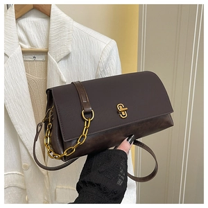 Detail of dark brown leather handbag with gold twist lock and chain strap on blazer