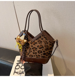 Detail of leopard print handbag with brown leather trim and cute bear keychain accessory