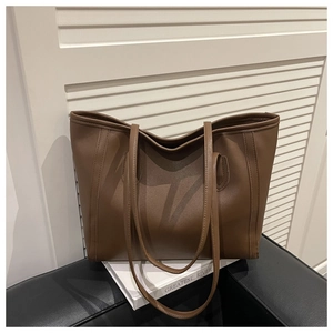 Detailed view of brown leather tote bag with fine stitching on a white book surface
