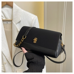 Close-up of black crossbody bag with vintage gold twist lock and metal chain detail