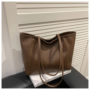 Detailed view of the brown leather tote bag texture and slim straps for daily use