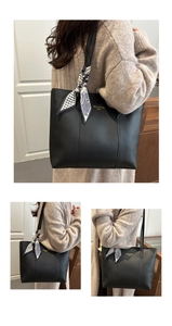 Detail of a black leather tote bag with a decorative scarf and gold brand lettering