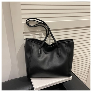 Close-up of matte black leather tote bag with vertical stitching and long shoulder straps