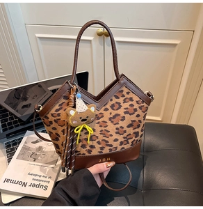 Close-up of leopard print handbag with brown leather trim and a cute teddy bear charm