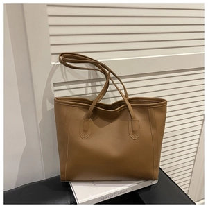Detail of a brown large capacity faux leather tote bag with elegant vertical stitching