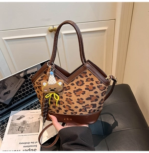 Detail of leopard print tote bag with plush bear charm and adjustable shoulder strap