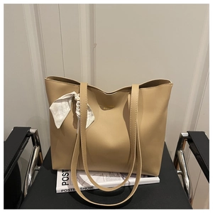 Detail of beige tote bag with soft leather texture and stylish floral silk scarf accessory