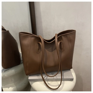 Close-up detail of the brown faux leather texture and minimalist shoulder strap design