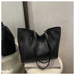 Detail of a minimalist black matte tote bag displayed on a sleek artistic pedestal