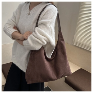 Detail of a large dark brown hobo tote bag with vertical stitching and matte texture