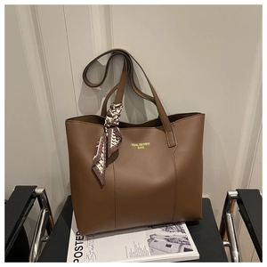 Detail of a brown tote bag with a decorative scarf on a leather chair