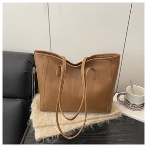 Brown textured leather tote bag with long straps displayed on a cozy knit fabric background