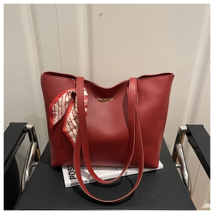 Detail of burgundy tote bag with matte leather texture and elegant red silk scarf