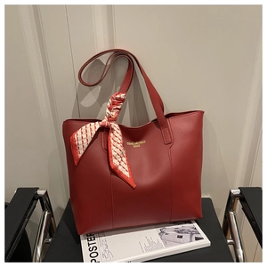 Detail of red leather tote bag with elegant silk scarf on a stylish black chair