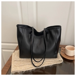 Detail of black matte leather tote bag with vertical stitching and dual shoulder straps