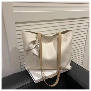 Detail of cream tote bag with stylish silk scarf and branded lettering on soft leather