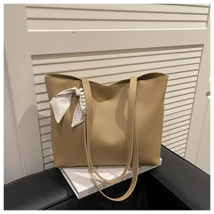 Large khaki leather tote bag featuring a decorative silk scarf and gold lettering details