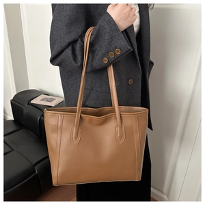 Detail view of large brown vintage tote bag with PU leather texture on a model shoulder